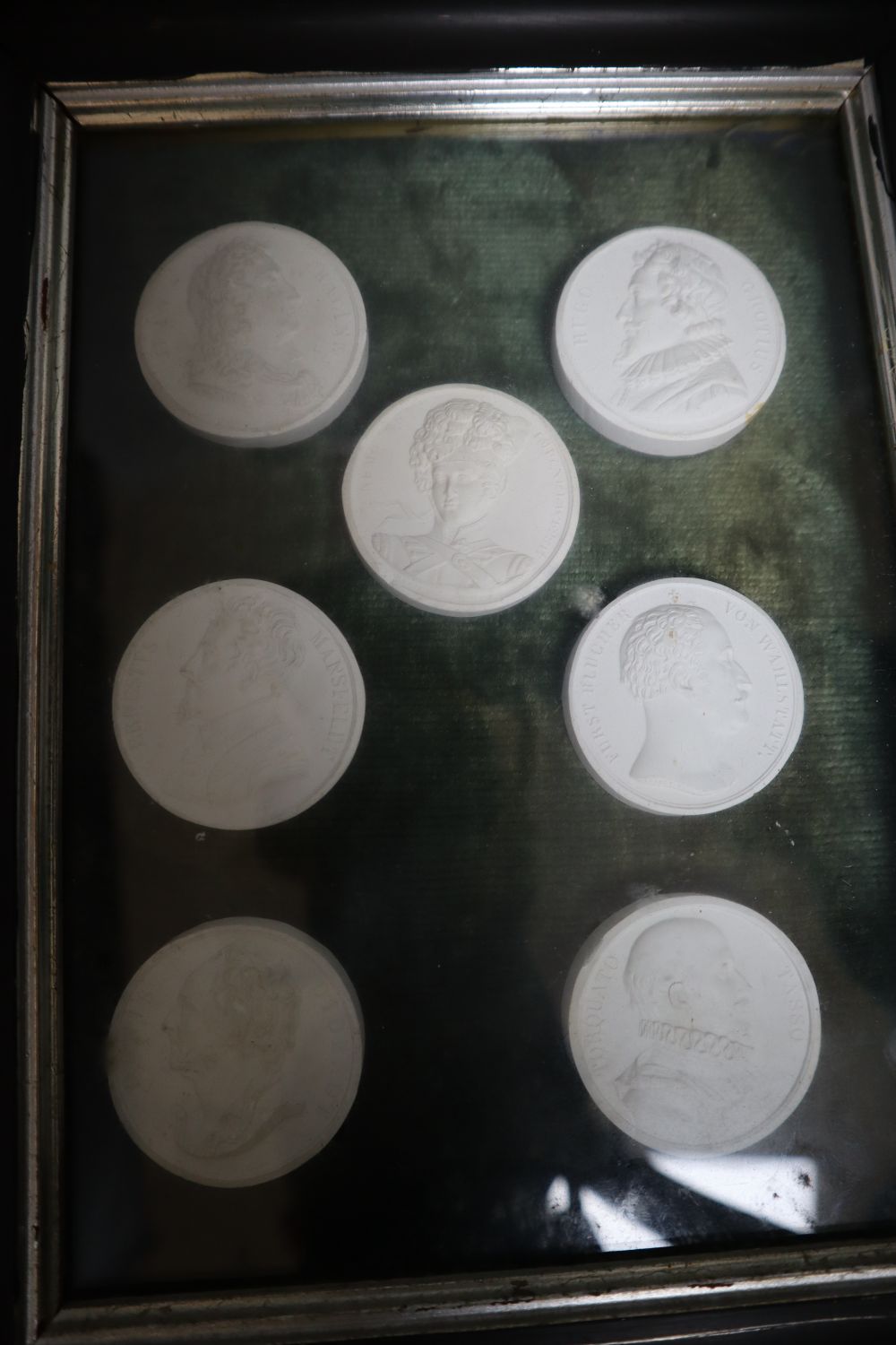 A collection of intaglio relief portrait plaques in a tray and a pair of framed sets